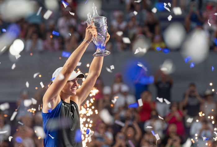 Iga Swiatek lifts the WTA finals trophy over her head